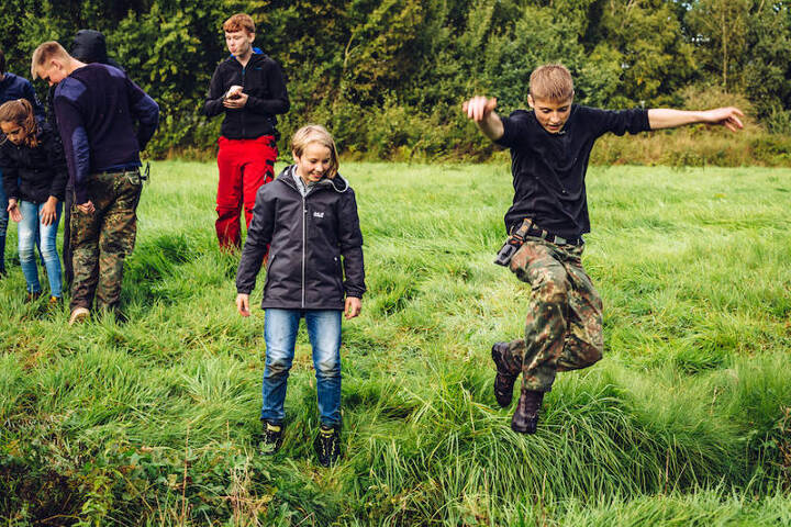 Jongen springt over beekje op survivalkamp.