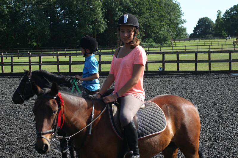 Meisje en jongen rijden op een pony tijdens ponykamp België