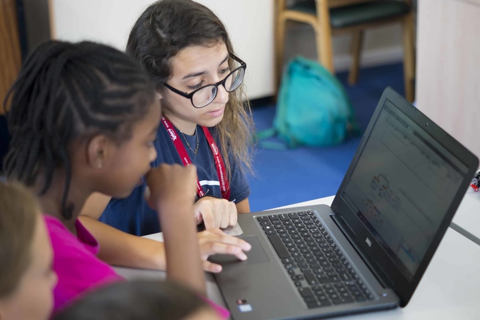Meisje toont ander meisje iets op computer tijdens Engels kamp