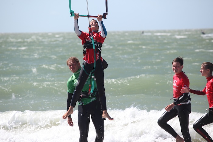 Jongen hangt aan een kite tijdens een kitesurf les op een kitesurfkamp