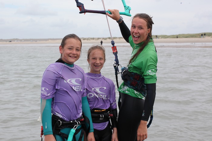 Meisjes lachen met de monitor voor de foto op kitesurfkamp Nederland
