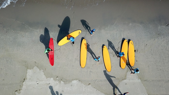 Bovenzicht van jongeren met surfboards op kitesurf kamp Nederland