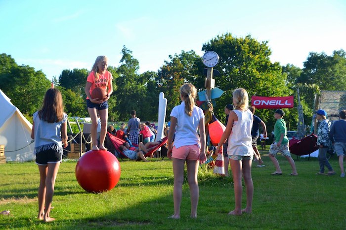 Deelnemers van surfkamp Nederland 13 jaar doen activiteiten met z'n allen op een grasveld