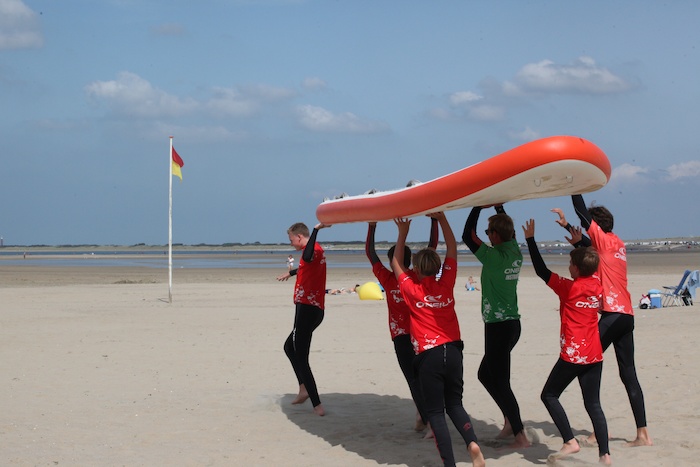 Kinderen houden een surfplank hoog tijdens een watersportkamp Nederland