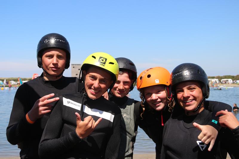 Deelnemers van surfkamp Zeeland staan op de foto met hun surf uitrusting aan