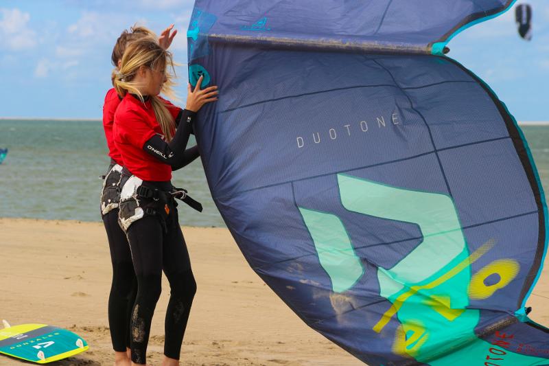 Twee meiden op het strand maken zich gereed voor een sessie kitesurfen tijdens een Watersportkamp