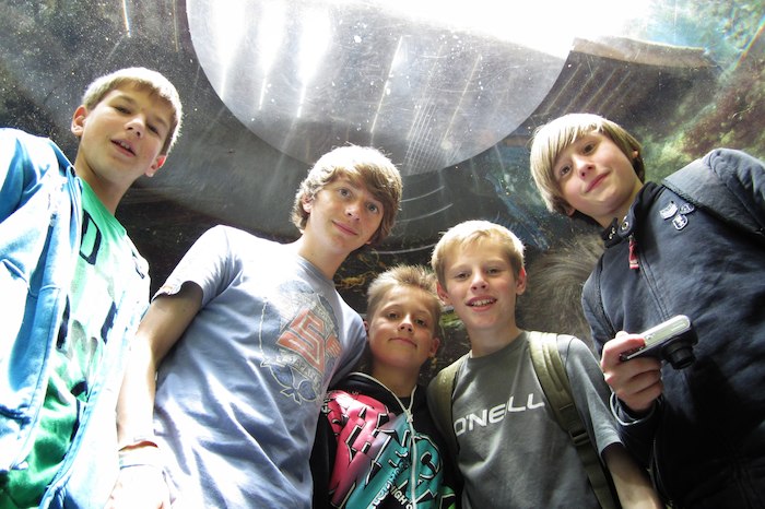Jongeren kijken neer op de camera, glimlachen op zomerkamp Gent.