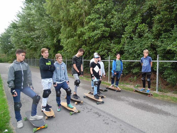 jongens staan op een skateboard op watersport kamp in de biesbosch