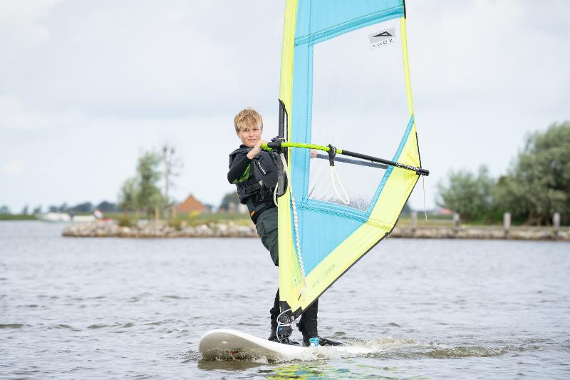 Een jongen leert windsurfen tijdens een surfkamp Nederland 14 jaar