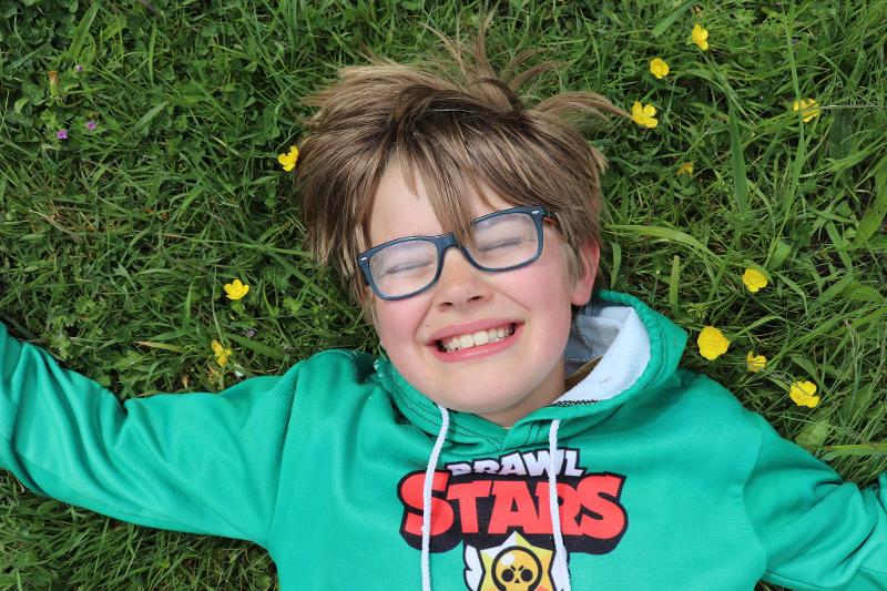 Jongen ligt op het gras tijdens kamp krokusvakantie