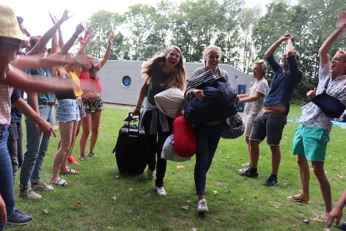 Meiden worden door andere deelnemers juichend verwelkomd op jongereis.