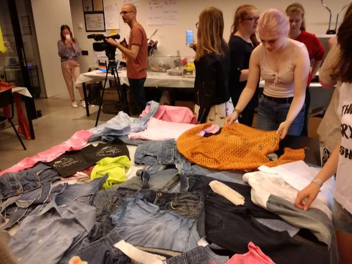 Meisjes kiezen verschillende stoffen tijdens het fashionkamp.