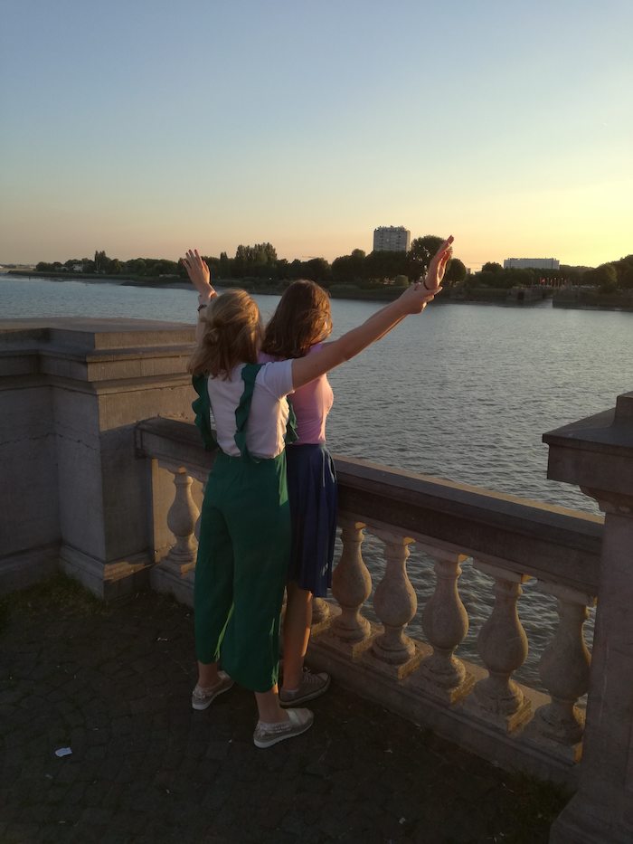 Twee meisjes genieten van de zonsondergang aan de Schelde op zomerkamp.