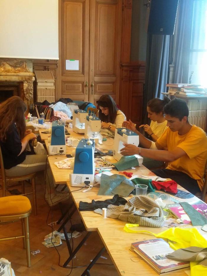 Jongeren naaien met machine tijdens het zomerkamp.