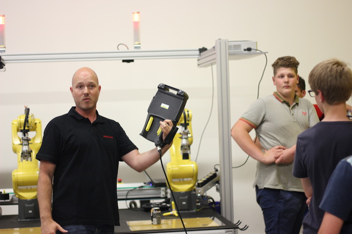 Man legt in robotfabriek iets uit aan de deelnemers