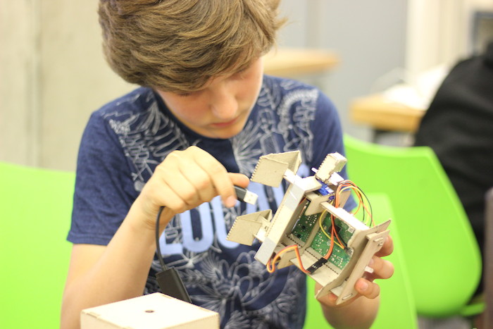 Jongen bouwt zijn eigen robot op zomerkamp.
