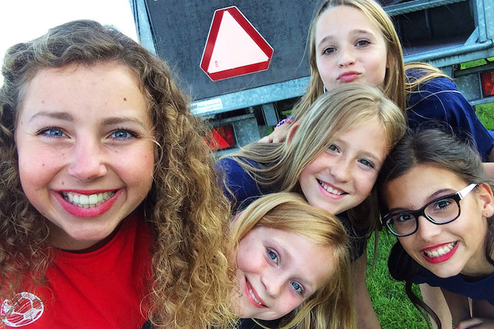 Begeleider en kinderen maken selfie tijden het meidenkamp