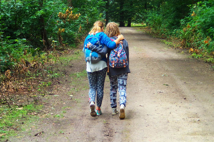 Vriendinnen lopen samen door het bos tijden meidenkamp