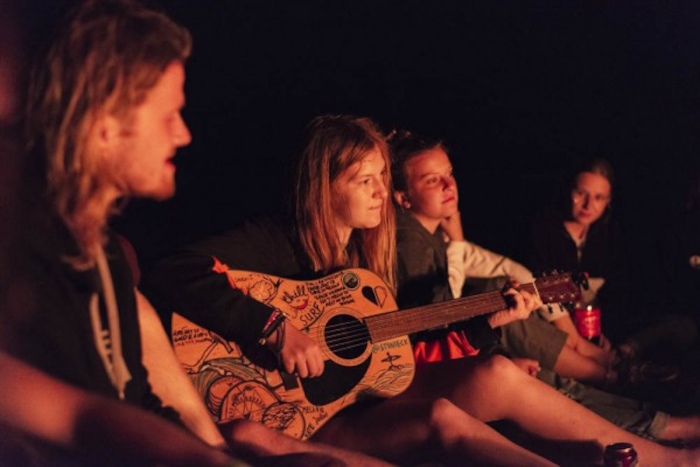 Des jeunes jouent de la guitare autour du feu en séjour linguistique anglais Belgique. 