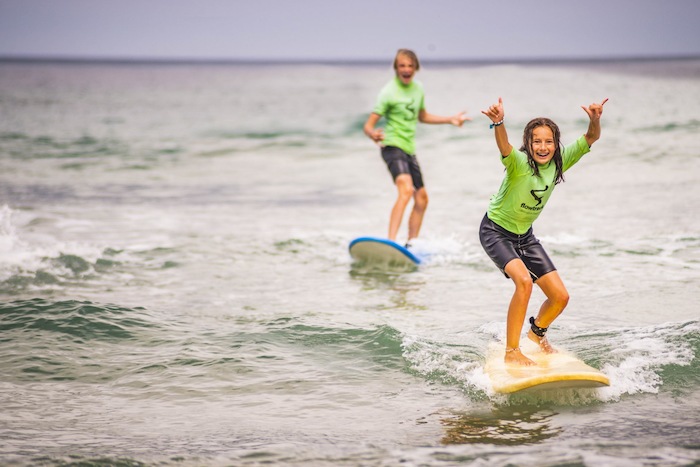 Meisje en jongen leren surfen in het buitenland.