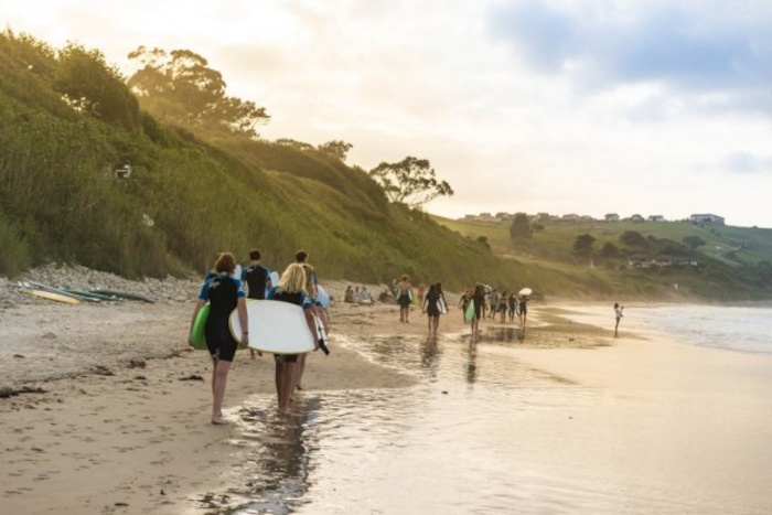 Tieners wandelen naar hun surfspot met hun board onder de arm.