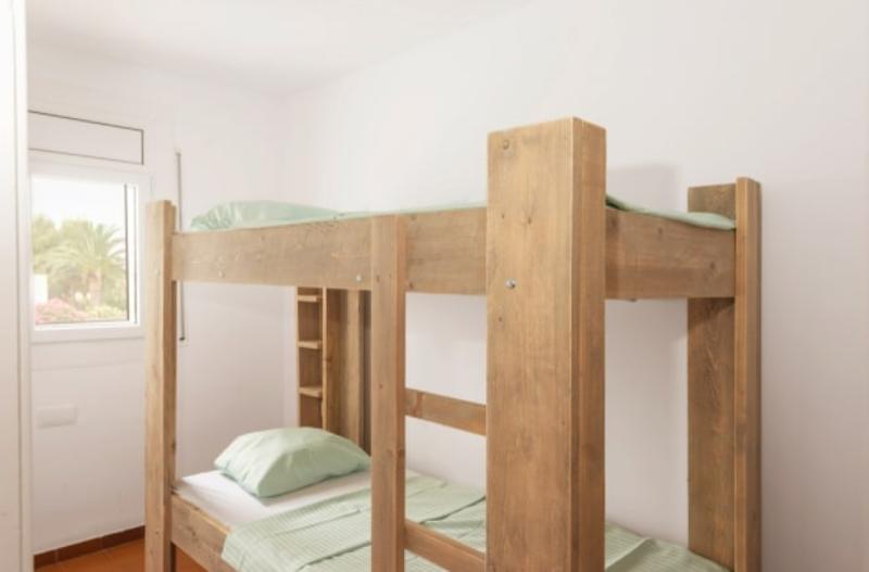 een houten stapelbed met groene bedlinnen op zomerkamp spanje watersportvakantie
