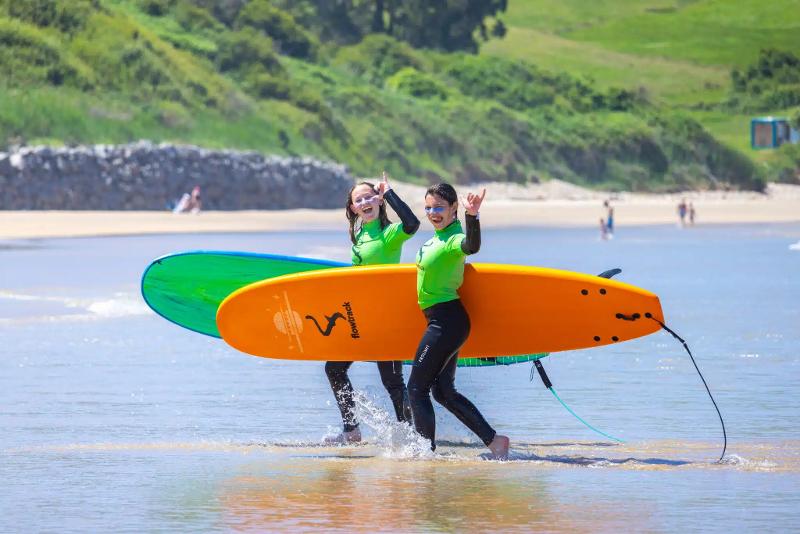 Meiden lopen het water in op surfvakantie Spanje