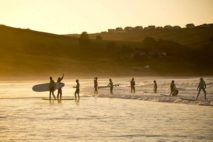Jongeren wandelen in de zon door het water tijdens een jongerenreis spanje surfkamp
