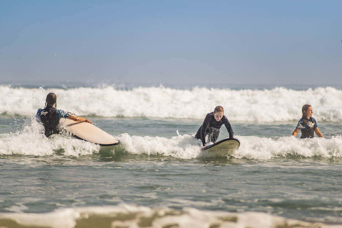 Jongeren surfen in wetsuits tijdens een jongerenreis spanje surfkamp