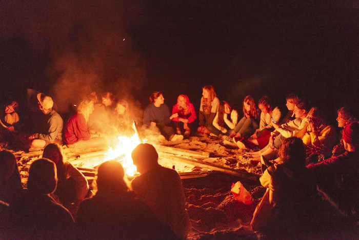 Jongeren chillen rond het kampvuur tijdens een jongerenreis spanje surfkamp