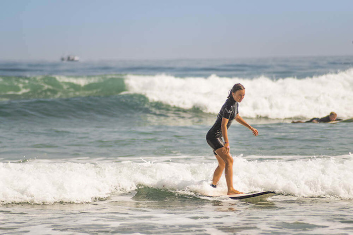 Meisje surft op surfkamp in Spanje over de golven tijdens een jongerenreis spanje surfkamp