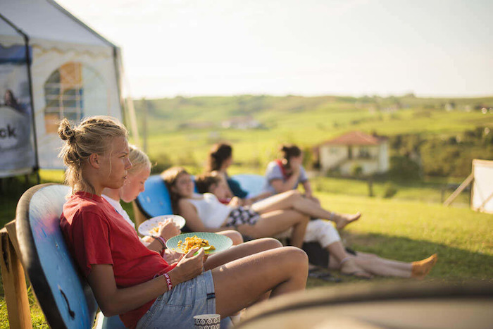 Meisjes eten in de zon tijdens het surfkamp in Spanje tijdens een jongerenreis spanje surfkamp