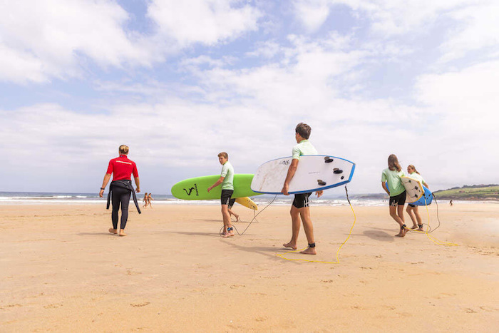 Jongeren steken het strand over om te gaan surfen tijdens een jongerenreis spanje surfkamp