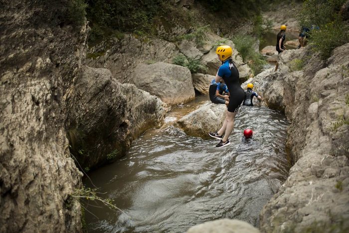 Jongeren springen van rotsen in Spanje tijdens een watersport vakantie