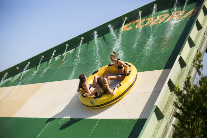 Meisjes glijden in een band bij hun bezoek aan het waterpretpark in Spanje tijdens een watersport vakantie