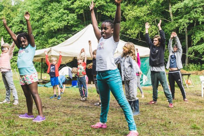Deelnemers op vakantiekamp staan met handen in de lucht