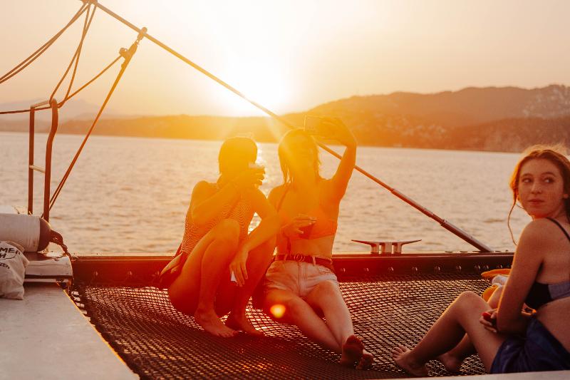Meiden genieten van de zon op een catamaran in Calella tijdens hun jongerenreis
