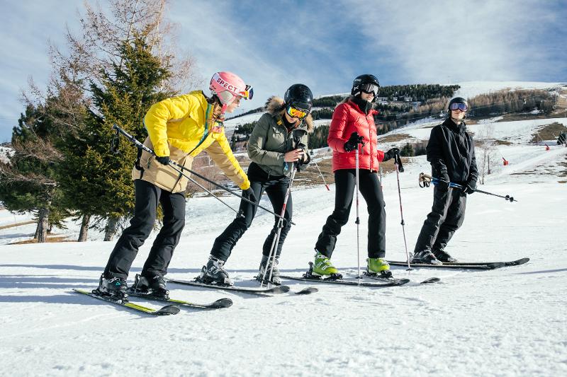 Vier mensen op skilatten op een rij in de sneeuw op groepsreis skivakantie