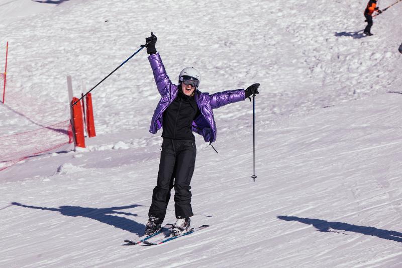 Een meisje op skilatten met de armen in de lucht op groepsreis skivakantie