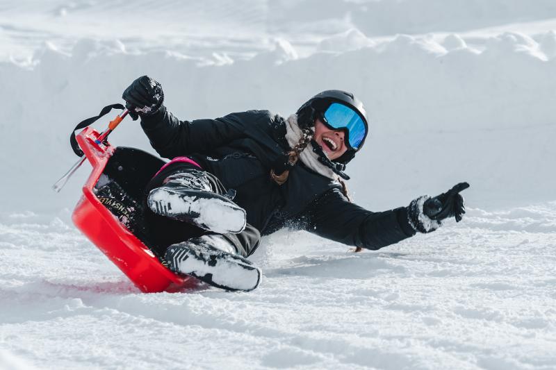 Een meisje op een slee in de sneeuw op groepsreis skivakantie