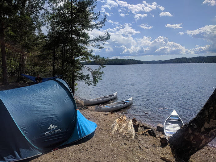 Een kano en tent bij het water tijdens de jongerenreis in Zweden.