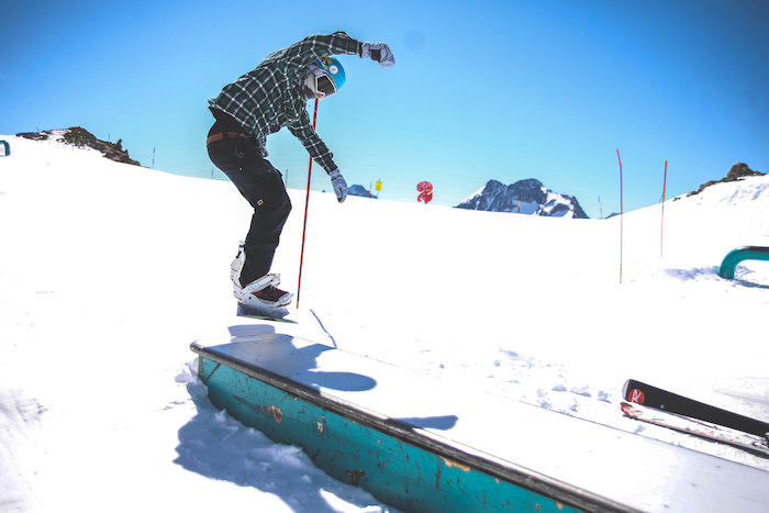 Jongen met snowboard springt op rails op skikamp