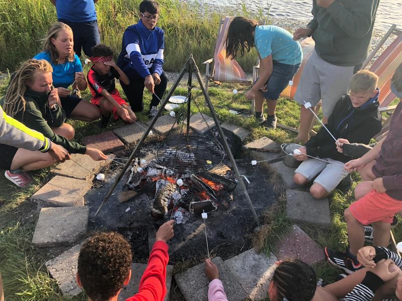 Kinderen zitten met marshmallows rond het vuur op kinderkamp
