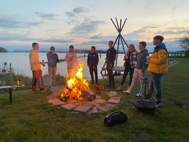 Een groep jongeren bij een kampvuur op jongerenvakantie in Nederland