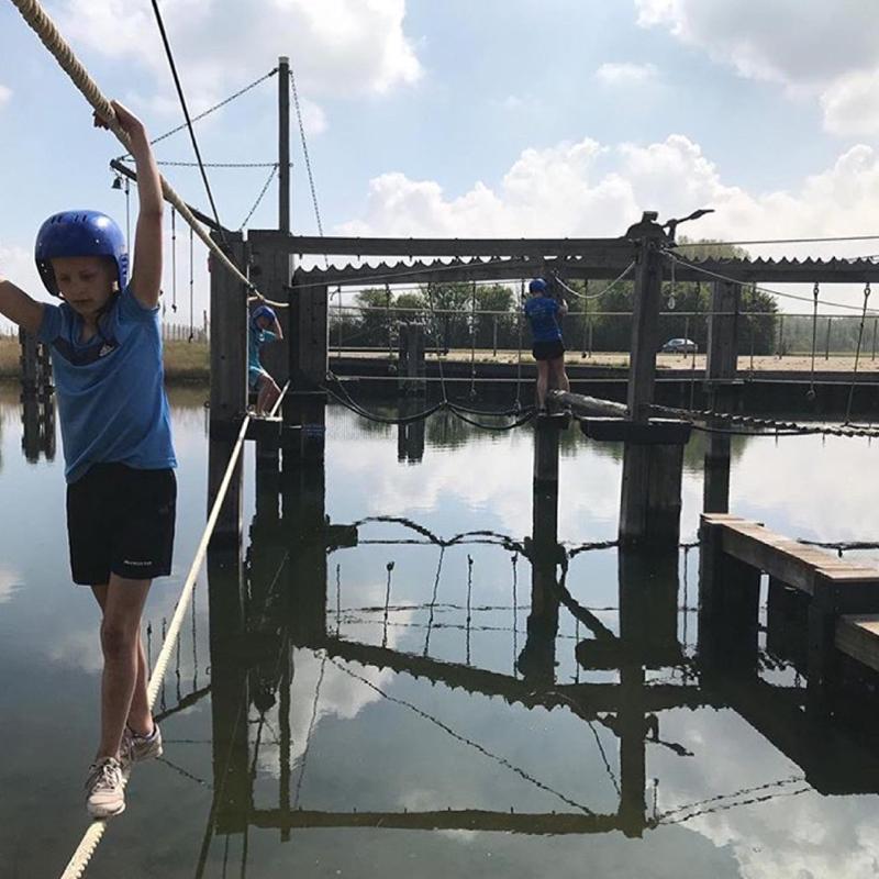 Kinderen klimmen op klimparcours boven water op kindervakantie