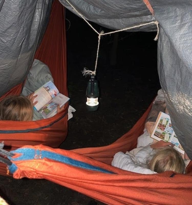 Kinderen lezen 's avonds in de hangmat op kindervakantie