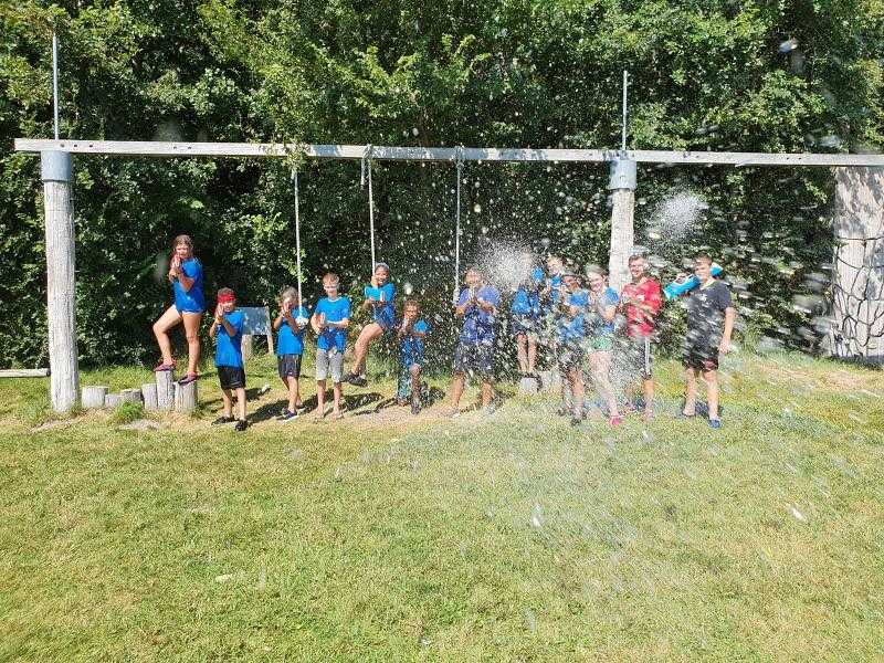 Groep kinderen schieten met waterpistolen naar camera op kindervakantie