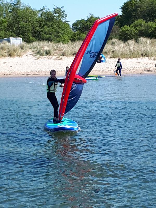 Jongen leert windsurfen op kindervakantie