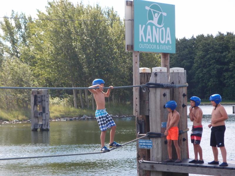 Jongen klimt op touw over water op kinderkamp