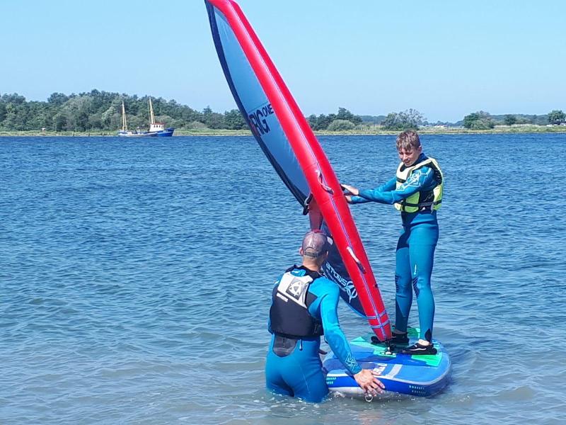 Jongen leert windsurfen op kinderkamp